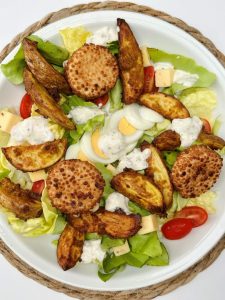 salade, oeuf dur, tomate, dés de gouda, fromage pané, potatoes et sauce crémeuse