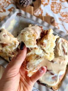 Gros plan sur un cinnamon roll moelleux au cœur fondant à la cannelle et au glaçage crémeux