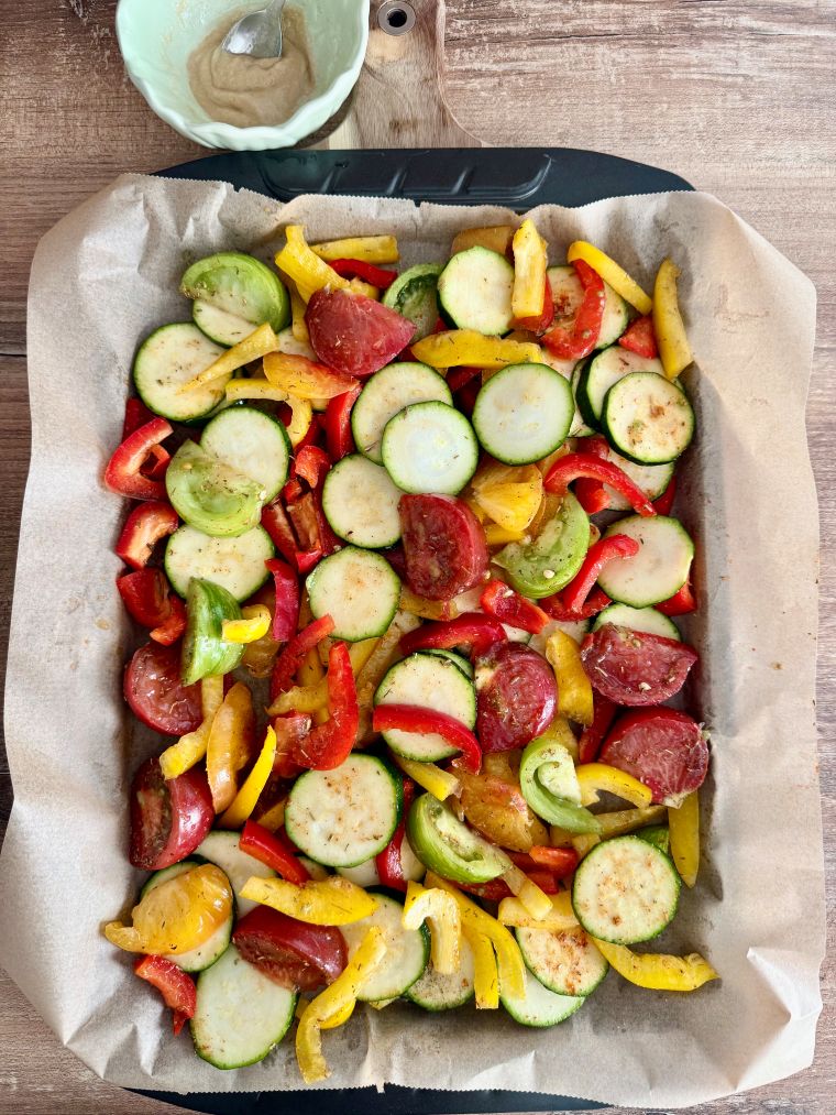 Poivrons, courgette et tomates coupés et épicés sur une plaque avant cuisson au four