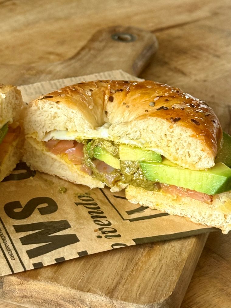 Coupe d'un sandwich bagel saumon avocat pesto oeuf