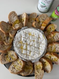 Tranches de baguette au levain à l'ail et à l'oignon disposées autour de la boîte de camembert