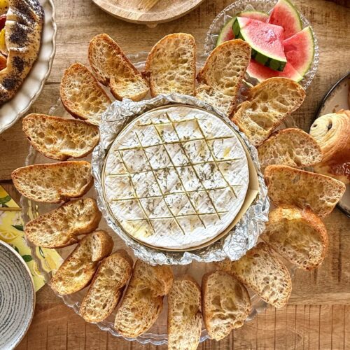 Camembert rôti au four au thym et miel sur la table, accompagné de toasts croustillants