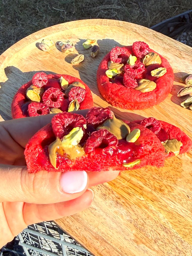 Cookie framboise pistache coupé en deux montrant le cœur fondant