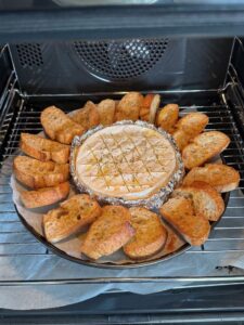 Cuisson du fromage au four dans sa boîte avec des toasts croustillants de baguette au levain