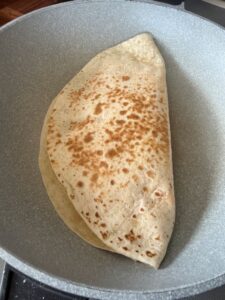 Quesadilla aux œufs brouillés en train de dorer dans une poêle chauffée à sec
