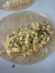 Tortilla garnie de tranches de cheddar, d'emmental et de mozzarella râpés puis d'œufs brouillés