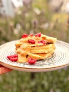 Pancake smoelleux au skyr avec un nappage de beurre de cacahuètes coulé sur les bananes et des framboises par-dessus