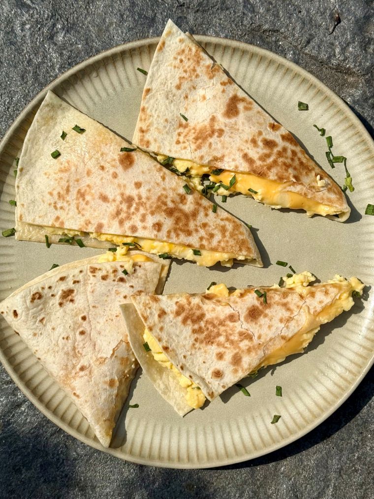 Quesadillas aux œufs brouillés et aux 3 fromages coupées en deux, fromage fondant qui file
