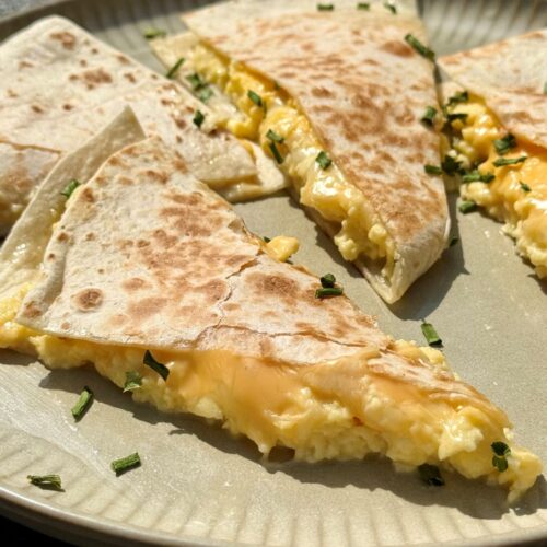 Quesadillas aux œufs brouillés et aux 3 fromages coupées en deux, fromage fondant qui file