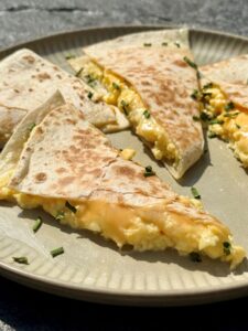 Quesadillas aux œufs brouillés et aux 3 fromages coupées en deux, fromage fondant qui file
