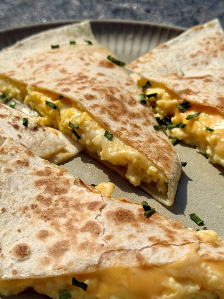 Quesadillas aux œufs brouillés et aux 3 fromages coupées en deux, fromage fondant qui file