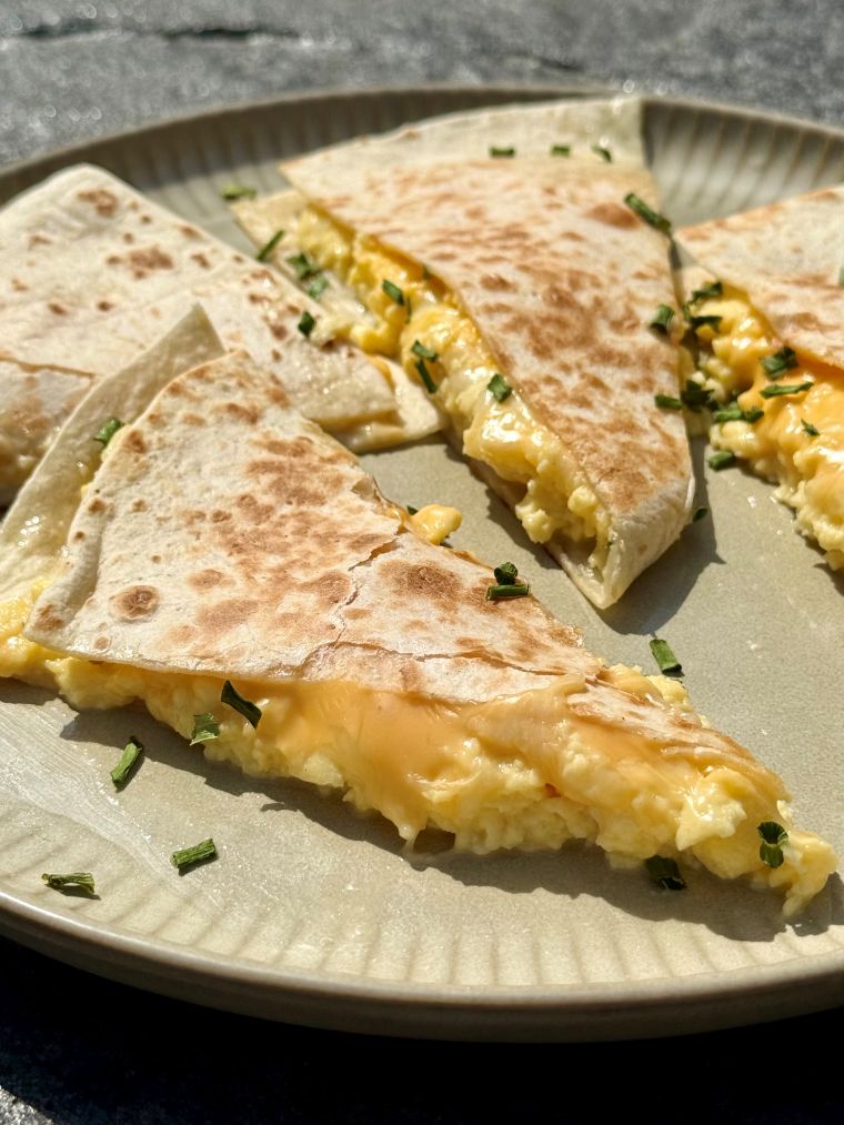 Quesadillas aux œufs brouillés et aux 3 fromages coupées en deux, fromage fondant qui file