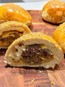 Bun burger coupé en deux posé sur une planche en bois, recette de buns burgers maison au four
