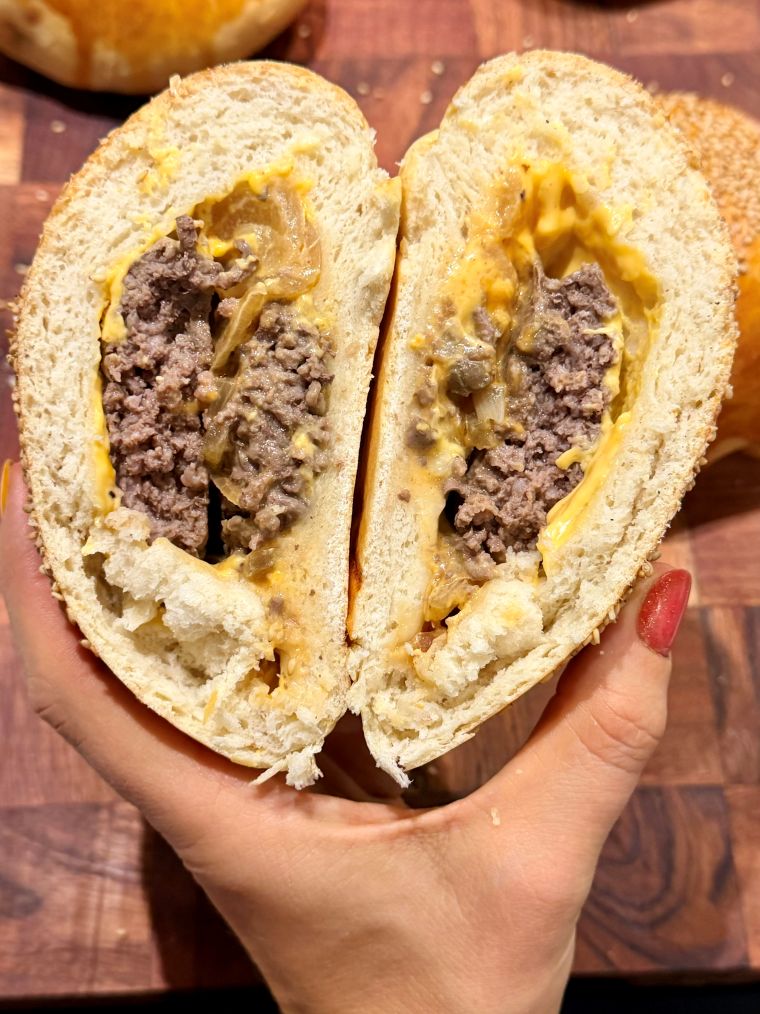 Gros plan sur l'intérieur d'un bun burger : deux steaks hachés de 70 g et cheddar fondu dans la mie briochée