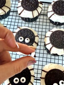 Mettre une goutte de chocolat fondu sur les yeux comestibles et poser sur les biscuits
